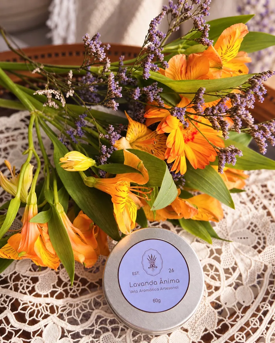 Vela Lavanda Ânima apresentada junto a flores alaranjadas e lilases